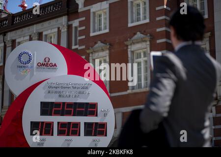 Les gens prennent des photos d'une horloge Omega, qui était auparavant utilisée comme horloge à rebours pour les Jeux Olympiques de Tokyo 2020 et qui affiche actuellement l'heure et la date actuelles, après l'annonce du report des Jeux à l'été 2021, à Tokyo, Japon, 25 mars 2020. (Photo par Alessandro Di Ciommo/NurPhoto) Banque D'Images