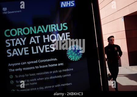 Un homme se fait le hérissons devant un panneau d'information numérique du coronavirus demandant aux gens de rester à la maison à l'arrêt de bus au Cirque Holborn à Londres, en Angleterre, sur 25 mars 2020. Autour d'un pays en grande partie fermé, le coronavirus Covid-19 continue de répandre l'anxiété et les perturbations, avec des conditions de verrouillage imposées lundi soir par le Premier ministre britannique Boris Johnson dès aujourd'hui dans leur deuxième jour. Il a été annoncé aujourd'hui que le prince Charles, héritier du trône britannique âgé de 71 ans, s'est révélé positif pour le coronavirus et a des « symptômes légers ». Au total, 468 personnes sont maintenant décédées après avoir été séropositives pour le coronavir Banque D'Images