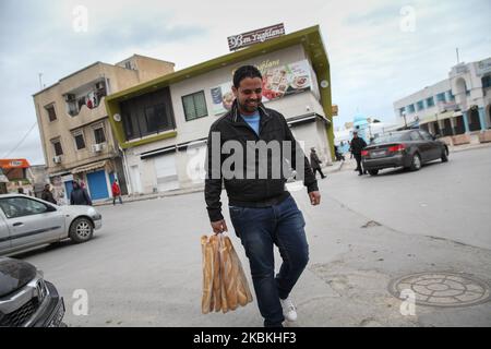 Un jeune homme tient un sac de pain alors qu'il marche dans la rue du centre-ville d'Ariana, dans le nord de la Tunisie, au troisième jour de l'isolement général imposé par les autorités afin de ralentir la propagation du nouveau coronavirus qui cause la maladie de Covid-19. Le gouvernorat d'Ariana a enregistré le deuxième plus grand nombre de cas confirmés de contamination par le coronavirus en Tunisie, à 24 mars 2020. (Photo de Chedly Ben Ibrahim/NurPhoto) Banque D'Images