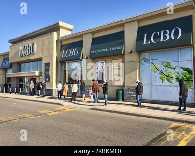 Une longue file de personnes attendant d'entrer dans un magasin de la LCBO (Commission de contrôle des alcools de l'Ontario) pour acheter de la bière et de l'alcool à Toronto, Ontario, Canada sur 27 mars 2020. Les magasins laissent entrer un nombre limité de personnes à la fois pour assurer la distanciation sociale (distanciation physique) afin de ralentir la propagation du nouveau coronavirus (COVID-19). Il a été interdit aux restaurants d'autoriser le service sur place et la province de l'Ontario a ordonné la fermeture des aires de restauration et des cafétérias. Les détaillants des centres commerciaux du Canada ont fermé leurs magasins en raison de l'épidémie de COVID-19. (Photo de Creative Tou Banque D'Images