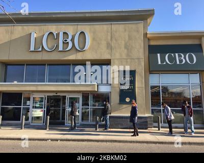 Une longue file de personnes attendant d'entrer dans un magasin de la LCBO (Commission de contrôle des alcools de l'Ontario) pour acheter de la bière et de l'alcool à Toronto, Ontario, Canada sur 27 mars 2020. Les magasins laissent entrer un nombre limité de personnes à la fois pour assurer la distanciation sociale (distanciation physique) afin de ralentir la propagation du nouveau coronavirus (COVID-19). Il a été interdit aux restaurants d'autoriser le service sur place et la province de l'Ontario a ordonné la fermeture des aires de restauration et des cafétérias. Les détaillants des centres commerciaux du Canada ont fermé leurs magasins en raison de l'épidémie de COVID-19. (Photo de Creative Tou Banque D'Images