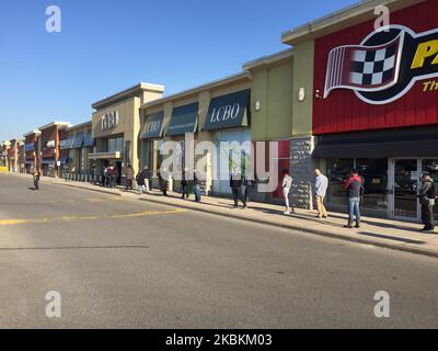 Une longue file de personnes attendant d'entrer dans un magasin de la LCBO (Commission de contrôle des alcools de l'Ontario) pour acheter de la bière et de l'alcool à Toronto, Ontario, Canada sur 27 mars 2020. Les magasins laissent entrer un nombre limité de personnes à la fois pour assurer la distanciation sociale (distanciation physique) afin de ralentir la propagation du nouveau coronavirus (COVID-19). Il a été interdit aux restaurants d'autoriser le service sur place et la province de l'Ontario a ordonné la fermeture des aires de restauration et des cafétérias. Les détaillants des centres commerciaux du Canada ont fermé leurs magasins en raison de l'épidémie de COVID-19. (Photo de Creative Tou Banque D'Images