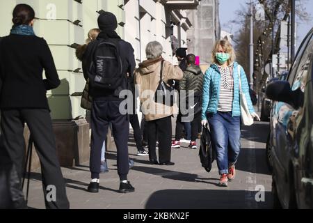 Une femme portant un masque protecteur dû à la propagation du coronavirus est vue passer par des personnes se tenant dans la ligne à une épicerie . Cracovie, Pologne sur 27 mars 2020. Le gouvernement polonais a décidé d'introduire de nouvelles limitations dans tout le pays, telles que des règles empêchant de quitter son pays, sauf si cela est justifié. (Photo de Beata Zawrzel/NurPhoto) Banque D'Images