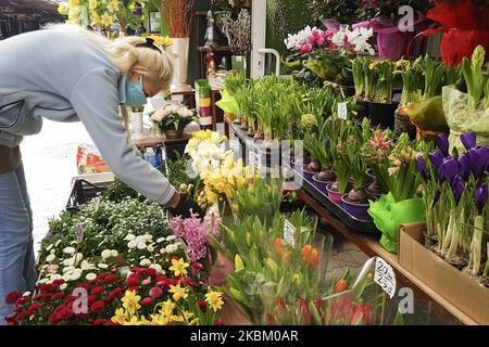 Une vendeuse porte un masque facial protecteur en raison de la propagation du coronavirus tout en vendant des fleurs de printemps et des décorations de Pâques sur le marché extérieur de Cracovie, en Pologne sur 4 avril 2020. Le gouvernement polonais a introduit de nouvelles restrictions strictes pour lutter contre les infections à COVID-19, comme empêcher de quitter la maison à moins que cela ne soit justifié, interdire aux enfants de moins de 18 ans de quitter la maison à moins d'être surveillés par un adulte, fermer l'accès aux parcs, boulevards, places et porter des gants pendant le shopping. (Photo de Beata Zawrzel/NurPhoto) Banque D'Images