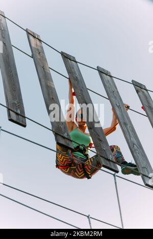 Grimpeur de roche adulte qualifié accroché à un mur de planches dans le parc d'aventure Banque D'Images