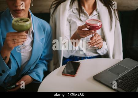 Gros plan des femmes d'affaires qui boivent du rose et du matcha latte tout en étant assis au café Banque D'Images