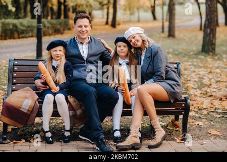 Une grande famille est assise sur un banc dans un parc d'automne. Des gens heureux dans le parc d'automne. Banque D'Images