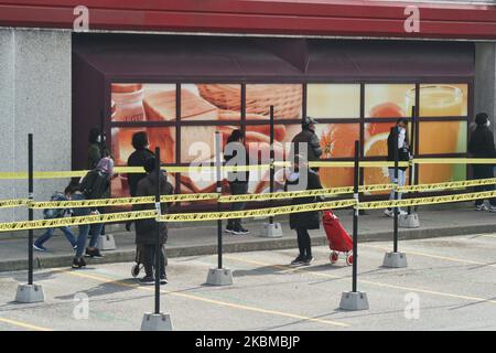 Longue ligne comme personnes pratiquant la distanciation sociale (distanciation physique) en attendant d'entrer dans un supermarché à Toronto, Ontario, Canada sur 12 avril 2020. Les magasins laissent entrer un nombre limité de personnes à la fois pour assurer la distanciation sociale (distanciation physique) afin de ralentir la propagation du nouveau coronavirus (COVID-19). (Photo de Creative Touch Imaging Ltd./NurPhoto) Banque D'Images