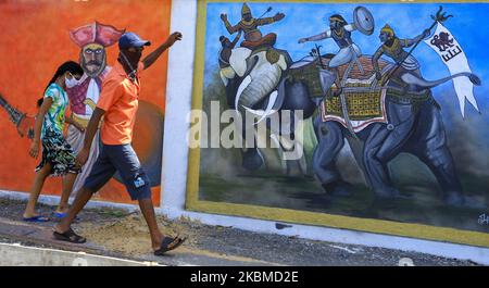 Un homme sri-lankais et sa fille portant des masques protecteurs marchent à côté d'une peinture murale d'un ancien bataillon sri-lankais engagé dans la guerre à Colombo, au Sri Lanka. 14 avril 2020. Malgré l'aube du nouvel an cinghalais et tamoul, les Sri Lankais se sont retirés des célébrations tandis que la police sri-lankaise a déclaré que les célébrations du nouvel an ont été interdites pendant les heures de couvre-feu, car le couvre-feu est imposé pour restreindre les mouvements des peuples dans le but de contenir la propagation du COVID-19. Selon le ministère sri-lankais de la Santé, 7 décès et 219 cas positifs de Covid-19 ont été signalés au Sri Lanka pendant qu'une île- Banque D'Images