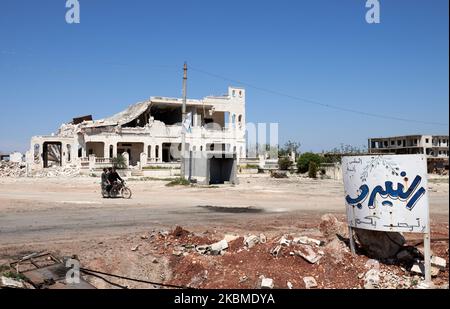 Les manifestants syriens passent un passe à moto près du panneau écrit en arabe signifie Bienvenue à Al-Nayrab, sur l'autoroute M4, où des dizaines de Syriens protestent contre des patrouilles militaires turco-russes sur l'autoroute M4, qui relie les provinces syriennes du nord d'Alep et de Latakia. Sur 14 avril 2020. (Photo par Karam Almasri/NurPhoto) Banque D'Images