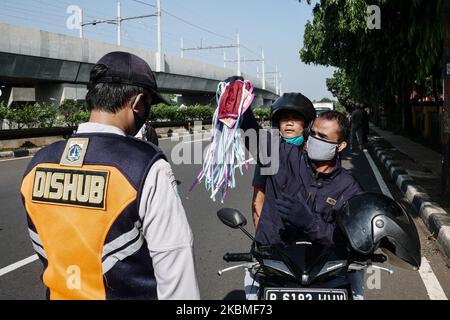 Un pilote montre un paquet de masque après avoir été invité à porter un masque par un agent de la circulation à un point de contrôle lors d'une restriction sociale à grande échelle (PSBB) à Jakarta, Indonésie sur 15 avril 2020. Le gouvernement de Jakarta applique officiellement des restrictions sociales à grande échelle (PSBB) exhorte les gens à garder la distance physique, en utilisant un masque et à réduire de 50% la capacité de transport du 10 au 24 avril dans le cadre des mesures de prévention de la propagation du coronavirus (COVID-19)., 2020. Le gouvernement de Jakarta met officiellement en œuvre des restrictions sociales à grande échelle (PSBB) exhorte les gens à garder la distance physique, en utilisant un M. Banque D'Images