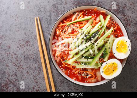 Nouilles froides épicées coréennes Bibim Guksu closeup dans le bol sur la table. Vue horizontale du dessus Banque D'Images