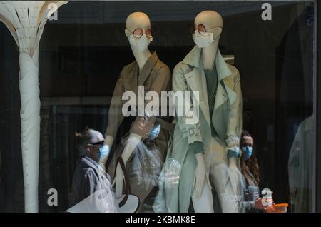 Les personnes portant des masques de protection passent devant une vitrine de la boutique de mode avec des mannequins portant des masques médicaux, au centre de Cracovie. Samedi, 18 avril 2020, à Cracovie, en Pologne. (Photo par Artur Widak/NurPhoto) Banque D'Images