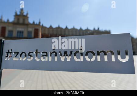 Le panneau rester à la maison reste sur la place du marché principal de Cracovie. A partir d'aujourd'hui (20 avril), l'interdiction de se déplacer, de voyager et de séjourner dans les lieux publics a été levée. Les parcs publics, les forêts et les plages ont été rouverts, à l'exception des terrains de jeux et des installations sportives. Les enfants de plus de 13 ans peuvent se déplacer sans parents. La couverture de la bouche et du nez en public reste obligatoire. Les terrains de jeux et les installations sportives restent fermés. Lundi, 20 avril 2020, à Cracovie, en Pologne. (Photo par Artur Widak/NurPhoto) Banque D'Images