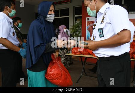 Les résidents reçoivent des sacs d'épicerie pendant la pandémie Covid-19 à la prison de Cipinang à Jakarta, on 23 avril,2020. Des centaines de gardiens ont donné des articles d'épicerie aux pauvres de la zone située à l'extérieur du complexe de logement du centre de détention. (Photo de Dasril Roszandi/NurPhoto) Banque D'Images