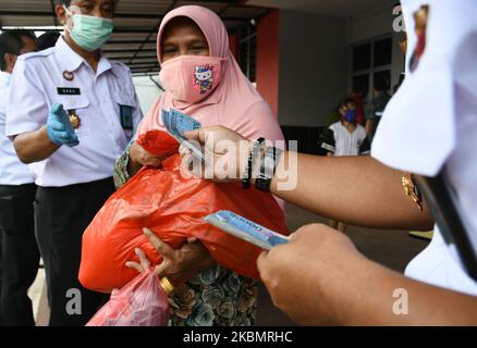 Les résidents reçoivent des sacs d'épicerie pendant la pandémie Covid-19 à la prison de Cipinang à Jakarta, on 23 avril,2020. Des centaines de gardiens ont donné des articles d'épicerie aux pauvres de la zone située à l'extérieur du complexe de logement du centre de détention. (Photo de Dasril Roszandi/NurPhoto) Banque D'Images