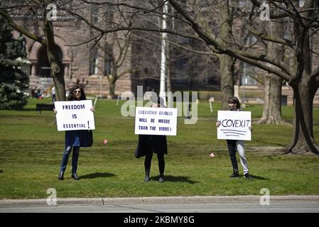 Des gens avec des panneaux et des bannières debout à côté de la rue pendant un rassemblement pour protester contre la fermeture provinciale et fédérale pour contrôler la propagation de Codid-19 au parc Queens à Toronto, au Canada, sur 25 avril 2020. (Photo par Arindam Shivaani/NurPhoto) Banque D'Images