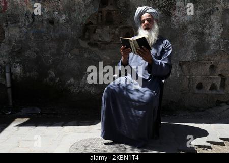 Un palestinien lit une copie du Coran, le livre le plus sacré de l'Islam, au milieu de la pandémie du coronavirus COVID-19, pendant le Saint mois de jeûne musulman du Ramadan devant son domicile, dans la bande de Gaza centrale, le 28 avril 2020. (Photo de Majdi Fathi/NurPhoto) Banque D'Images