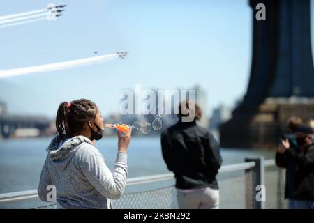 Une jeune femme souffle des bulles tandis que les US Navy Blue Angels et les Thunderbirds de l'USAF font un passage bas au-dessus du pont de Manhattan de la ville de New York lors de leur tour du moral du coronavirus aux États-Unis, le mardi 28 avril 2020. (Photo par B.A. Van Sise/NurPhoto) Banque D'Images