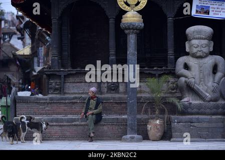 Un vieil homme qui offre de la nourriture à un chien en face du temple de Dattatreya pendant le confinement complet de la nation comme préoccupations au sujet de la propagation du virus de Corona (COVID-19) à Bhaktapur, Népal mercredi, 29 avril 2020. (Photo de Narayan Maharajan/NurPhoto) Banque D'Images