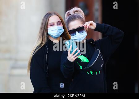 Des filles portant des masques protecteurs en raison de la propagation du coronavirus sont vues prendre des selfies sur la place principale de Cracovie, en Pologne, sur 28 avril 2020. La règle de la couverture du nez et de la bouche dans les lieux publics avec des masques faciaux, des charves ou des mouchoirs est entrée en vigueur à partir de 16 avril. L'ordonnance ne s'applique pas aux enfants jusqu'à l'âge de deux ans et aux personnes qui ne peuvent pas couvrir leur bouche ou leur nez en raison de difficultés respiratoires. (Photo de Beata Zawrzel/NurPhoto) Banque D'Images