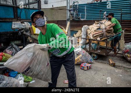 Les collecteurs d'ordures chargent le camion-citerne avec les déchets ménagers d'un quartier de Quezon City, Philippines, sur 29 avril 2020. Également salués comme des frontaux, les collecteurs d'ordures continuent à travailler en contact étroit avec différents déchets malgré les risques pour la santé et le manque d'équipement de protection individuelle (EPI). À ce jour, les Philippines ont enregistré un total de 8 212 cas de COVID-19, 558 décès et 1 023 reprises (photo de Lisa Marie David/NurPhoto). Banque D'Images