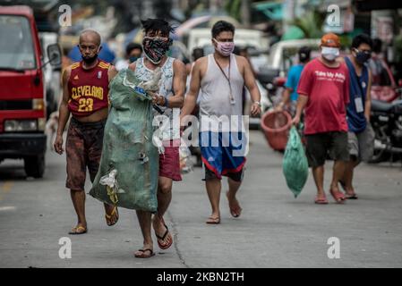 Les résidents apportent leurs déchets ménagers aux collecteurs d'ordures à Quezon City, Philippines, sur 29 avril 2020. Également salués comme des frontaux, les collecteurs d'ordures continuent à travailler en contact étroit avec différents déchets malgré les risques pour la santé et le manque d'équipement de protection individuelle (EPI). À ce jour, les Philippines ont enregistré un total de 8 212 cas de COVID-19, 558 décès et 1 023 reprises (photo de Lisa Marie David/NurPhoto). Banque D'Images