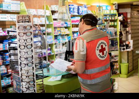 Un volontaire de la Croix-Rouge recueille des médicaments auprès d'une pharmacie pour les livrer à des personnes vulnérables et isolées dans le cadre du programme « Croix-Rouge chez vous ». L'association offre un service d'écoute et de fourniture de nécessités de base aux personnes vulnérables et isolées qui ne peuvent pas faire leurs courses pendant la détention, à Paris, en France, sur 21 avril 2020. (Photo par Emeric Fohlen/NurPhoto) Banque D'Images