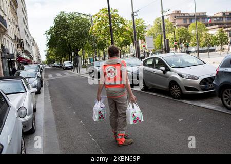 Un volontaire de la Croix-Rouge recueille des médicaments auprès d'une pharmacie pour les livrer à des personnes vulnérables et isolées dans le cadre du programme « Croix-Rouge chez vous ». L'association offre un service d'écoute et de fourniture de nécessités de base aux personnes vulnérables et isolées qui ne peuvent pas faire leurs courses pendant la détention, à Paris, en France, sur 21 avril 2020. (Photo par Emeric Fohlen/NurPhoto) Banque D'Images