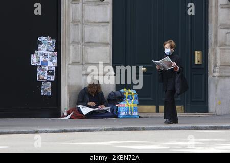 Une femme lit son journal et marche sur un front un sans-abri qui lit son journal à Saint Germain des Prés à Paris, comme un verrouillage est imposé pour ralentir le taux de la maladie du coronavirus (COVID-19) en France, 2 mai 2020. (Photo de Mehdi Taamallah / NurPhoto) (photo de Mehdi Taamallah / NurPhoto) Banque D'Images