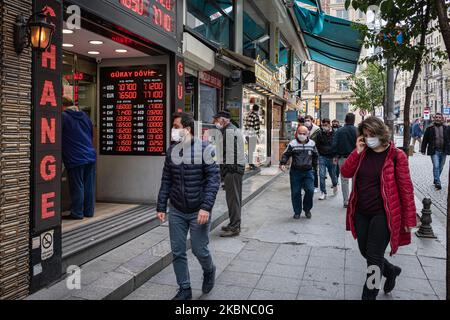 Le 5 mai 2020, les résidents d'Istanbul, le centre de la pandémie de Covid-19 en Turquie, portaient des masques lorsqu'ils magasinaient dans le quartier historique d'Eminonu, où de nombreux magasins restent fermés en raison des restrictions imposées pour enrayer la propagation du coronavirus. De telles précautions pèsent lourdement sur l'économie turque et sur la lire turque, qui est tombée à sa plus faible valeur depuis la crise financière de cette semaine. Au-dessus, les Turcs marchent près d'un magasin de change dans le quartier Eminonu de Fatih, Istanbul. (Photo de Diego Cupolo/NurPhoto) Banque D'Images