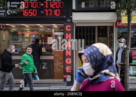 Le 5 mai 2020, les résidents d'Istanbul, le centre de la pandémie de Covid-19 en Turquie, portaient des masques lorsqu'ils magasinaient dans le quartier historique d'Eminonu, où de nombreux magasins restent fermés en raison des restrictions imposées pour enrayer la propagation du coronavirus. De telles précautions pèsent lourdement sur l'économie turque et sur la lire turque, qui est tombée à sa plus faible valeur depuis la crise financière de cette semaine. Au-dessus, les Turcs marchent près d'un magasin de change dans le quartier Eminonu de Fatih, Istanbul. (Photo de Diego Cupolo/NurPhoto) Banque D'Images