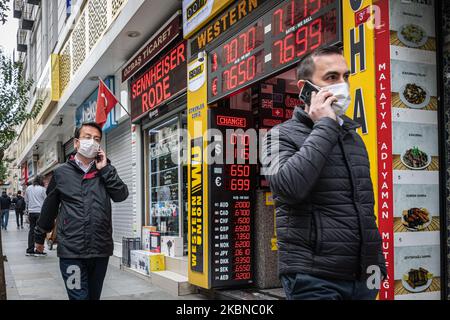 Le 5 mai 2020, les résidents d'Istanbul, le centre de la pandémie de Covid-19 en Turquie, portaient des masques lorsqu'ils magasinaient dans le quartier historique d'Eminonu, où de nombreux magasins restent fermés en raison des restrictions imposées pour enrayer la propagation du coronavirus. De telles précautions pèsent lourdement sur l'économie turque et sur la lire turque, qui est tombée à sa plus faible valeur depuis la crise financière de cette semaine. Au-dessus, des hommes turcs marchent près d'un magasin de change dans le quartier Eminonu de Fatih, Istanbul. (Photo de Diego Cupolo/NurPhoto) Banque D'Images