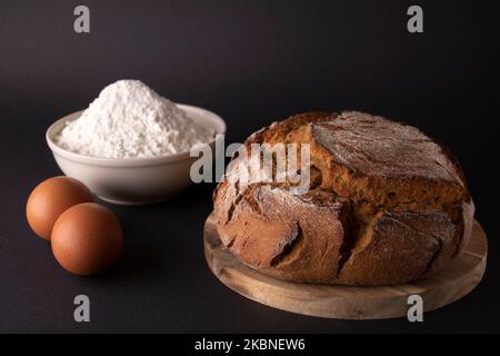 le pain fait maison se trouve sur le plateau de cuisine, à côté de la farine et des œufs Banque D'Images