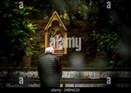 Un croyant aîné prie devant la grotte de Lourdes à Oostakker - Belgique le 08 mai 2020. Normalement, en mai, il est très occupé dans et autour de la cité de pèlerinage, en l'honneur de notre Dame de Lourdes réputée avoir des propriétés de guérison. Par la crise de la couronne (COVID19) aucun événement n'a lieu en raison d'un verrouillage strict à travers la Belgique pour arrêter la propagation de la pandémie de COVID-19, causée par le nouveau coronavirus. Les croyants sont autorisés à se promener et à prier et à allumer une bougie dans la basilique. Une grotte de Lourdes est une réplique de la grotte originale de Lourdes en France. (Photo de Jonathan Raa/NurPhoto) Banque D'Images