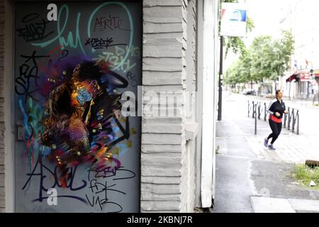 Une femme court un front une peinture signée par l'artiste de rue français C215 appelé l'Amour à l'époque du coronavirus, comme un verrouillage est imposé pour ralentir le taux de la maladie du coronavirus (COVID-19) à Ivry sur Seine près de Paris en France, 10 mai 2020. (Photo de Mehdi Taamallah/NurPhoto) Banque D'Images