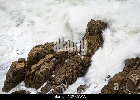 Une vague de l'océan s'écrasant sur des rochers le long de la côte d'Hermanus, le mouvement a erré en raison de la vitesse d'obturation lente. Whale Coast, Overberg, Western Banque D'Images