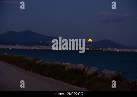 L'éblouissant Super Flower Moon de mai 2020 comme vu s'élevant au-dessus de la mer Égée et de la ville de Thessalonique en Grèce de Kalochori sur 7 mai 2020. La montée de la dernière superlune de 2020 apparaît sur les collines de la ville de Thessalonique, brille dans le ciel grec méditerranéen et se reflète sur la mer illuminant la nuit sombre. (Photo de Nicolas Economou/NurPhoto) Banque D'Images