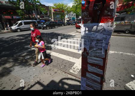 Une vue de la mère et d'un enfant passe devant des affiches et une salle de publicité pour les loyers en espagnol le long de Roosevelt Ave. Pendant la pandémie du coronavirus à 27 mai 2020, dans la ville de New York. Les directives gouvernementales encouragent le port d'un masque en public avec une forte distanciation sociale en vigueur puisque les 50 États des États-Unis ont commencé un processus graduel pour rouvrir lentement après des semaines de séjour à la maison mesures pour ralentir la propagation de COVID-19. (Photo de John Nacion/NurPhoto) Banque D'Images