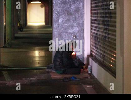 Un homme sans domicile portant une veste d'édredon illumine sa cigarette par terre devant un magasin fermé, à Ximen, dans la ville de Taipei, le 27 mai 2020, dans le contexte de la pandémie Covid-19. (Photo de CEng Shou Yi/NurPhoto) Banque D'Images