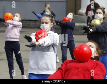 Les gymnastes de l'école Deriugina portant des masques protecteurs dans le cadre de l'épidémie du coronavirus Covid-19 prennent part à une séance de formation dans une rue du centre de Kiev, en Ukraine, le 01 juin 2020. Les jeunes gymnastes ont suivi une formation dans une rue pour soutenir l'action 'Save Deriugina School', qui a été organisée à l'appui de l'Irina Deryugina école de gymnastique pour enfants et jeunes. (Photo par STR/NurPhoto) Banque D'Images