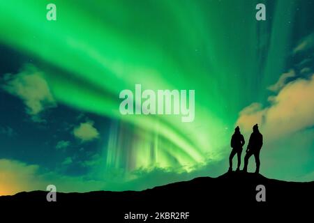 Une silhouette de jeune couple aventureux regardant les lumières du nord aussi connu sous le nom d'aurora borealis Banque D'Images