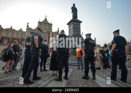 Un groupe de jeunes activistes LGBT vus pendant la vérification d'identité de la police à côté du monument Adam Mickiewicz, sur la place du marché principal de Cracovie. Une douzaine de jeunes activistes ont répondu par leur présence à un événement non officiel Facebook appelé "Une discothèque Rainbow sur la place principale". Après environ 15min de l'événement, les activistes ont pris une photo de groupe au monument Mickiewicz. Quelques minutes plus tard, deux pistes avec des membres de la police locale sont arrivées et ont commencé à vérifier les pièces d'identité des activistes et ainsi mettre fin à l'événement. Le lundi 12 vendredi 2020, à Cracovie, en Pologne. (Photo par Artur Widak/NurPhoto) Banque D'Images