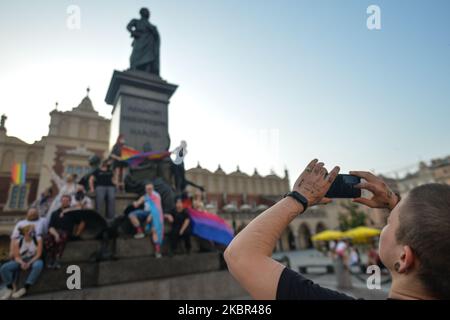 Un groupe de jeunes portant des drapeaux LGBT ont vu danser à côté du monument Adam Mickiewicz, sur la place du marché principal de Cracovie. Une douzaine de jeunes activistes ont répondu par leur présence à un événement non officiel Facebook appelé "Une discothèque Rainbow sur la place principale". Après environ 15min de l'événement, les activistes ont pris une photo de groupe au monument Mickiewicz. Quelques minutes plus tard, deux pistes avec des membres de la police locale sont arrivées et ont commencé à vérifier les pièces d'identité des activistes et ainsi mettre fin à l'événement. Le lundi 12 vendredi 2020, à Cracovie, en Pologne. (Photo par Artur Widak/NurPhoto) Banque D'Images