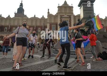 Un groupe de jeunes portant des drapeaux LGBT ont vu danser à côté du monument Adam Mickiewicz, sur la place du marché principal de Cracovie. Une douzaine de jeunes activistes ont répondu par leur présence à un événement non officiel Facebook appelé "Une discothèque Rainbow sur la place principale". Après environ 15min de l'événement, les activistes ont pris une photo de groupe au monument Mickiewicz. Quelques minutes plus tard, deux pistes avec des membres de la police locale sont arrivées et ont commencé à vérifier les pièces d'identité des activistes et ainsi mettre fin à l'événement. Le lundi 12 vendredi 2020, à Cracovie, en Pologne. (Photo par Artur Widak/NurPhoto) Banque D'Images