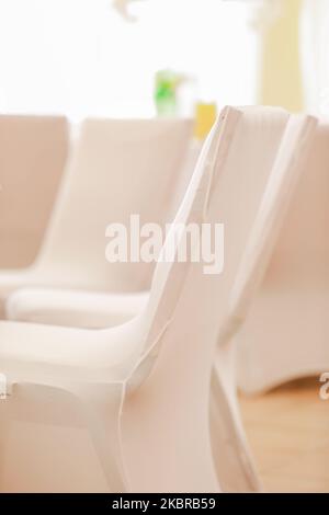 Chaises de banquet recouvertes de tissu blanc disposées dans la rangée pour préparer la réception de la cérémonie Banque D'Images