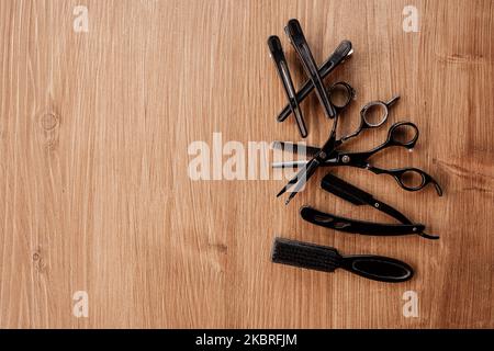 Équipement de salon de coiffure sur fond de bois avec place pour le texte. Composition de pose à plat avec sabot, ciseaux, rasoir vintage pour le rasage de la barbe, tissu noir Banque D'Images