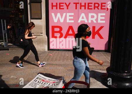 Une femme portant un masque passe devant une pile de journaux du soir, déclarant « LockDown Over », à Oxford Circus à Londres, en Angleterre, sur 23 juin 2020. Le Premier ministre britannique Boris Johnson a annoncé aujourd'hui que la prochaine étape de l'assouplissement du confinement en Angleterre se ferait selon les horaires, avec des pubs, des restaurants, des hôtels, des coiffeurs, théâtres, cinémas, musées, galeries, bibliothèques, Parcs à thème et zoos autorisés à rouvrir de 4 juillet. La règle de distance sociale de deux mètres doit également être réduite de moitié à partir de la même date, et les gens sont encouragés à prendre des mesures d'atténuation supplémentaires, comme porter le visage c Banque D'Images