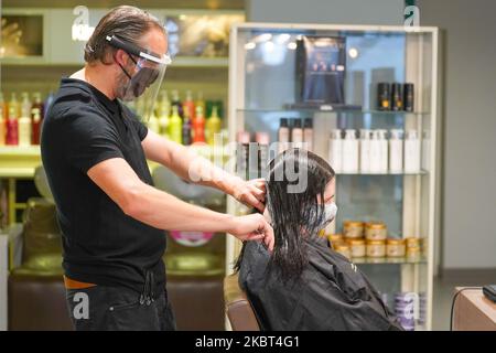 Conrad Blandford, propriétaire du salon de coiffure Conrad Blandford, Sheffield porte un équipement de protection individuelle (EPI) et un masque de protection pour le visage travaille avec les cheveux d'un client à Sheffield, Royaume-Uni sur 4 juillet 2020 car la facilité de verrouillage permet aux salons de coiffure de rouvrir à travers le Royaume-Uni. Le propriétaire du salon de coiffure Conrad Blandford a mis aux enchères leur premier poste de coupe de cheveux verrouillé, élevant un chiffre stupéfiant de £180 à être donné au NHS dans le cadre de leurs célébrations d'anniversaire de 72nd. Pubs, restaurants, salons de coiffure, théâtres, musées et galeries rouvriront sur 4 juillet, après un confinement national contre la propagation de la Banque D'Images