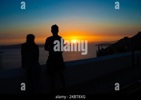 Un couple de touristes américains apprécient le coucher du soleil. Vue sur le coucher du soleil depuis Thera sur l'île de Santorin, Cyclades dans la mer Egée en Grèce. Quelques touristes et les habitants apprécient le coucher de soleil magique sur le volcan à Fira alors que le pays a ouvert les aéroports et a permis aux touristes de venir après 1 juillet en raison de la pandémie du coronavirus Covid-19 mesures générales de confinement qui ont commencé à se relâcher depuis 15 juin. La Grèce a récemment rouvert la saison touristique d'été avec le Premier ministre Kyriakos Mitsotakis ayant un discours de Santorin pendant le coucher du soleil pour relancer la saison touristique que l'économie grecque est fortement ba Banque D'Images